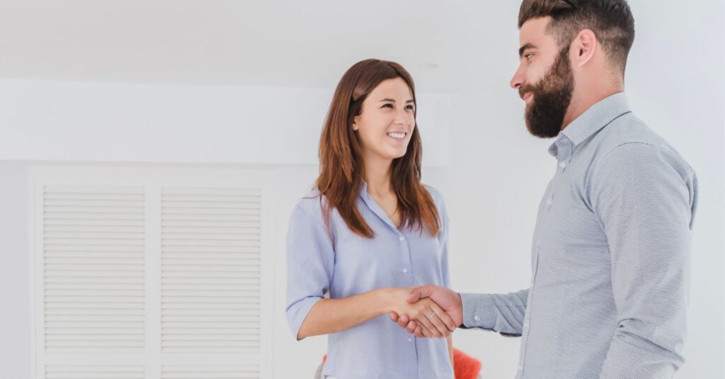Pareja firmando un divorcio de mutuo acuerdo de forma amistosa y cerrando el pacto con un apretón de manos